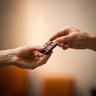 Hands sharing a piece of homemade vegan chocolate, symbolizing community and sharing