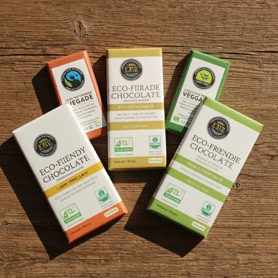 Assortment of eco-friendly vegan chocolate bars with various certifications like Fair Trade and Organic, on a rustic wooden background, natural lighting, no text, no words, no typography, no labels, clean image